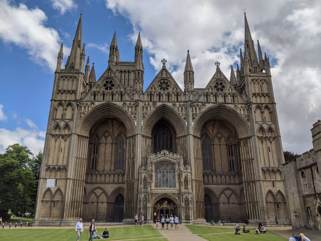 Detailed Gothic architecture of Peterborough Cathedral with visitors on the lawn, relevant to local web development projects in Peterborough